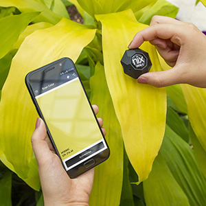 A hand holds a Nix sensor to a leaf and the colour of the leaf transfers to a mobile phone.