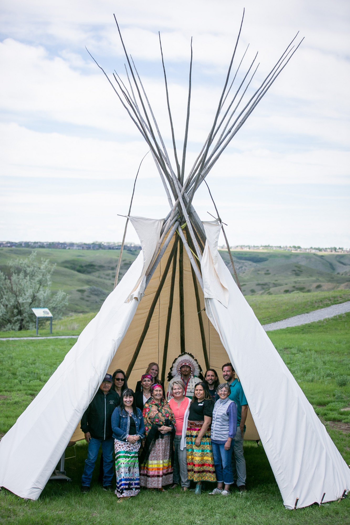 a group of people standing inside a tipi smiling at camera