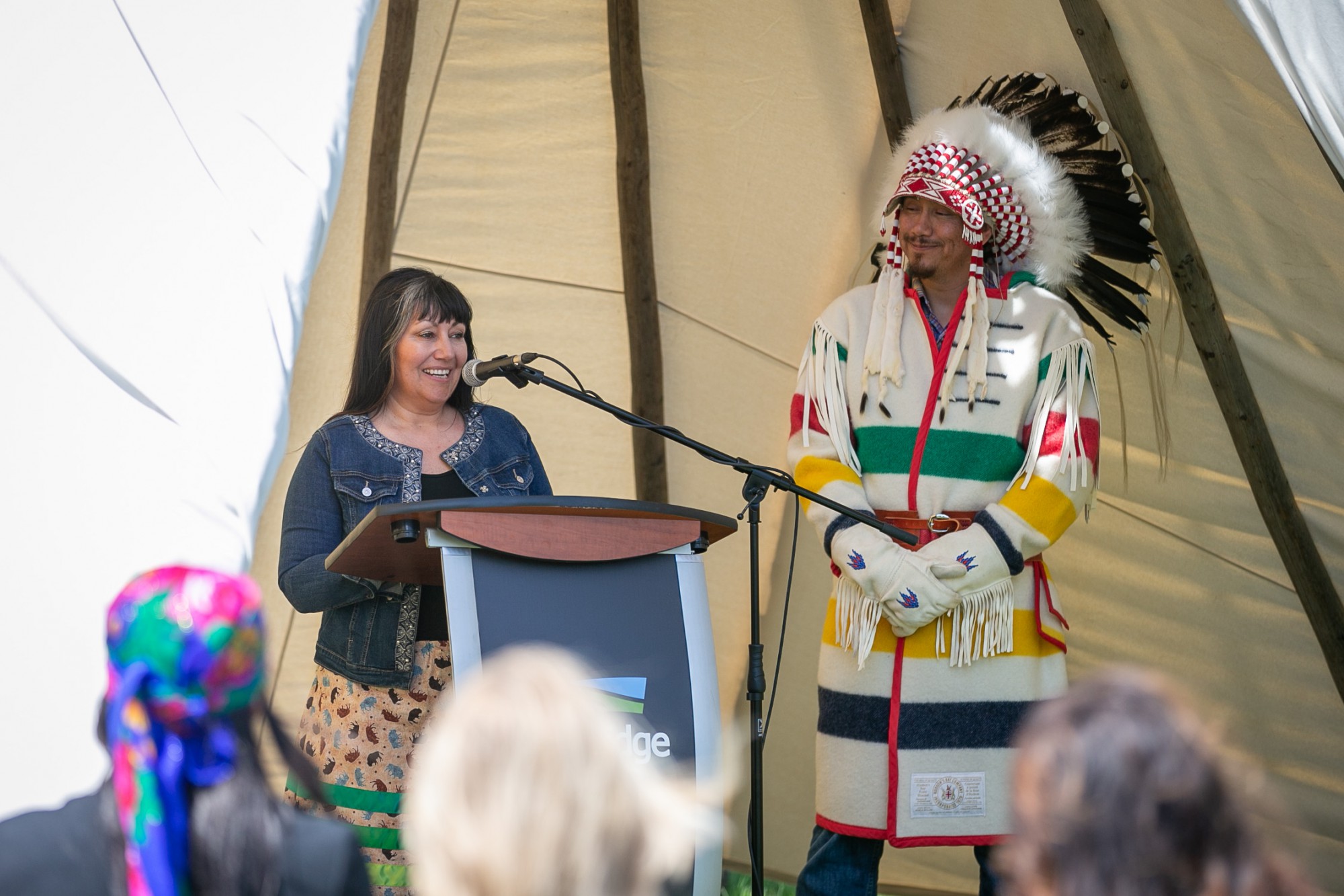 two people stand at a podium inside a tipi