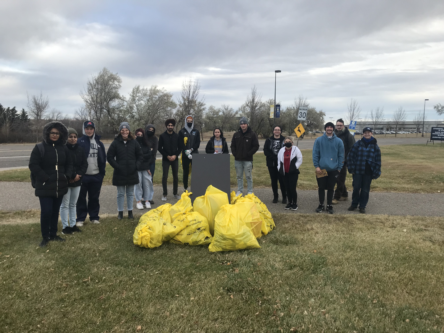 a group of people pose in front of several large yellow garbage bags