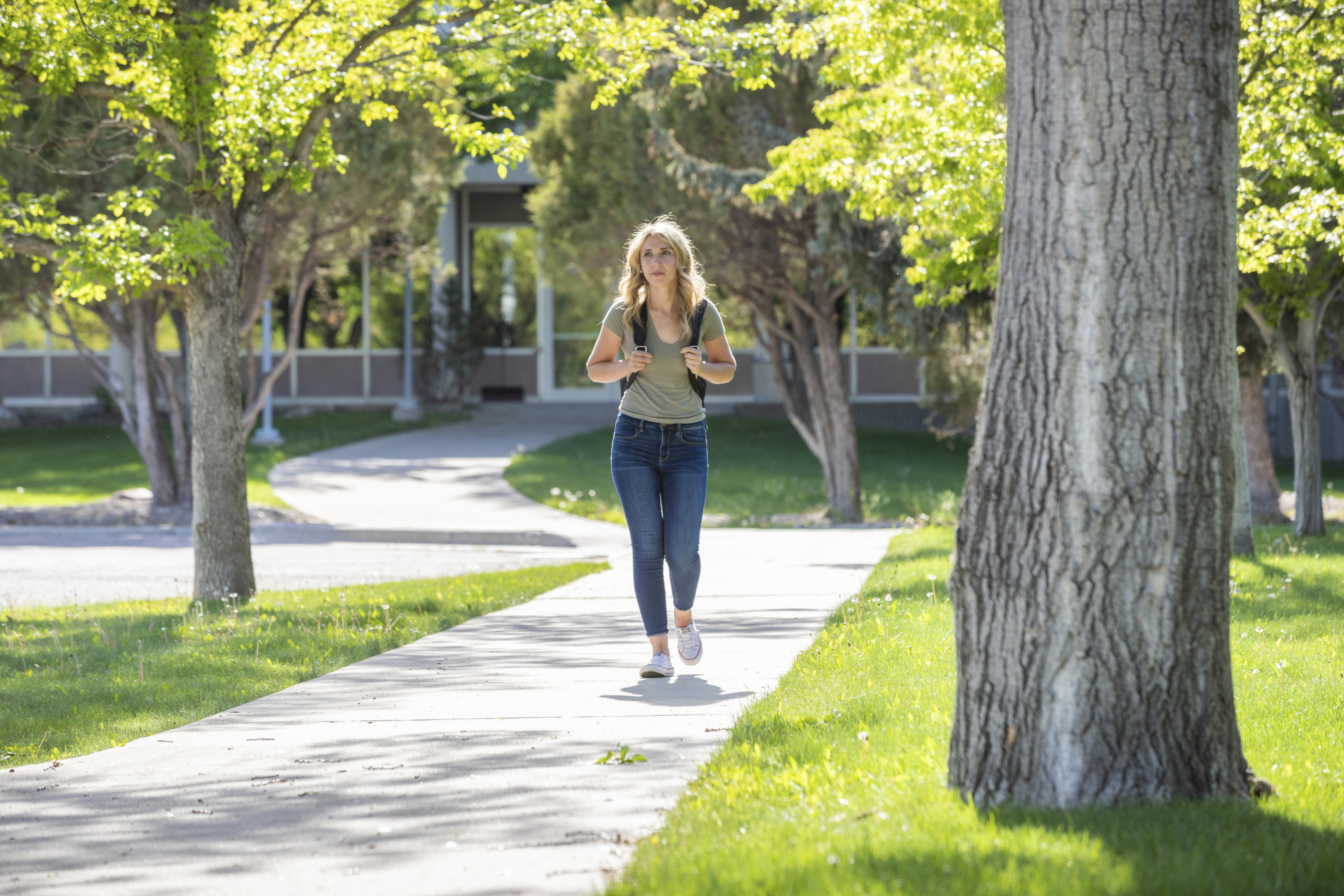 A student wearing a backpack, walks outside campus