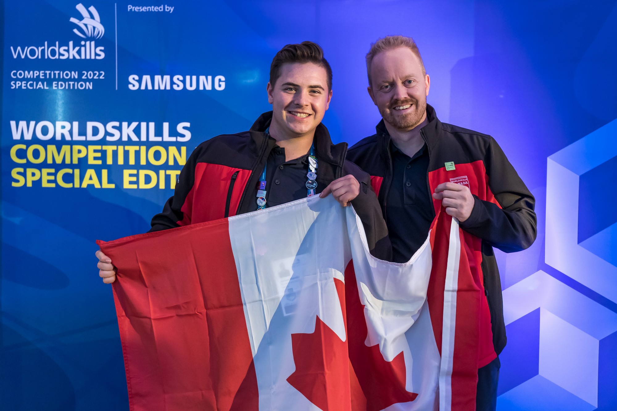 two people hold a Canada flag and smile for the camera