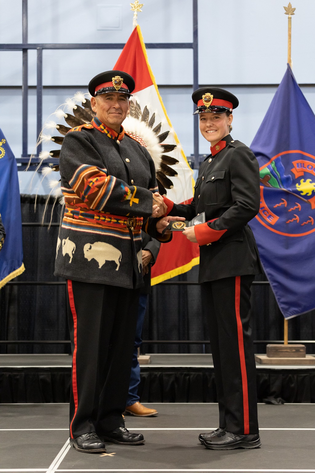 A police chief shakes hands with a police cadet graduate
