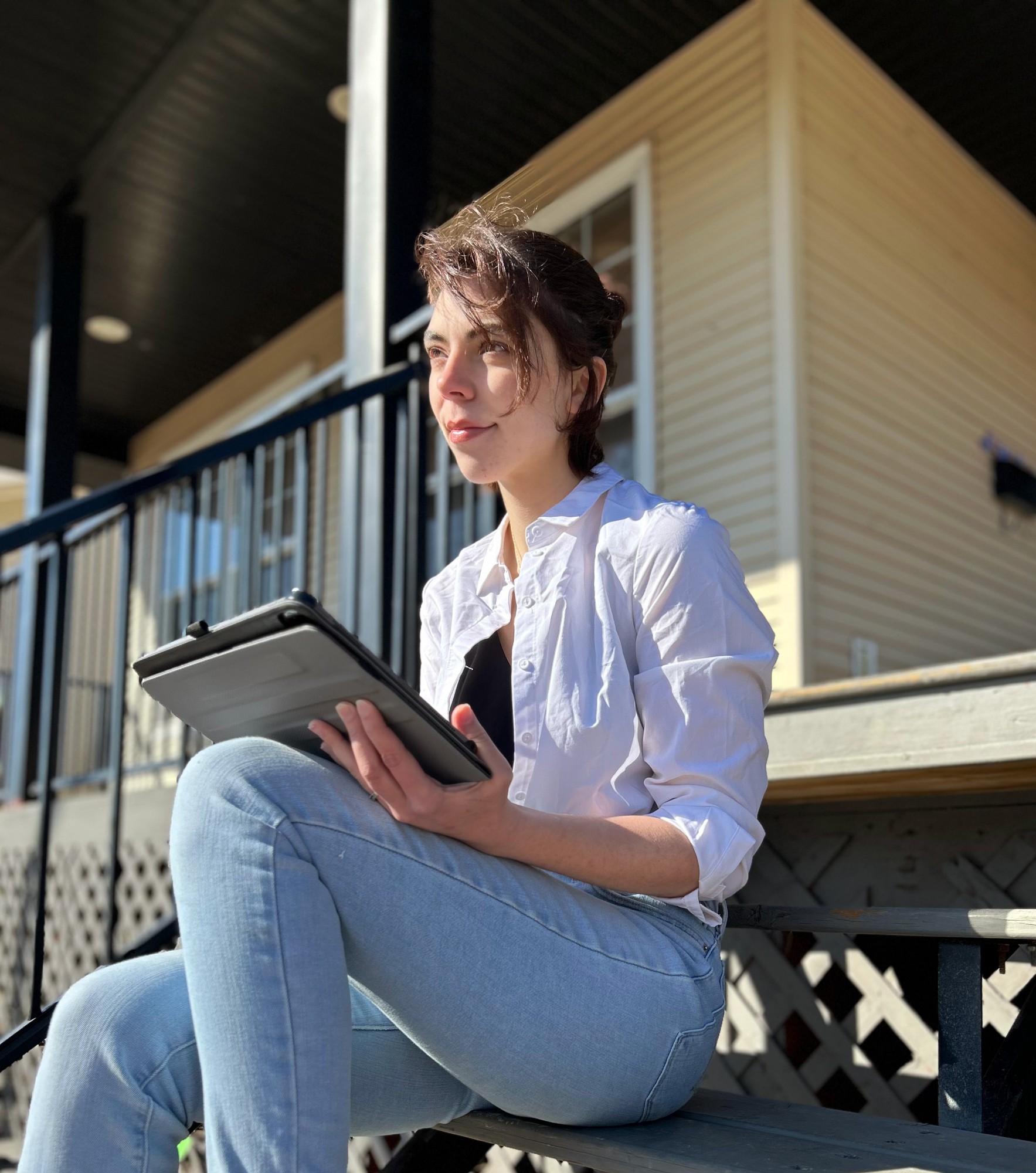 a young woman sitting on porch steps with an ipad