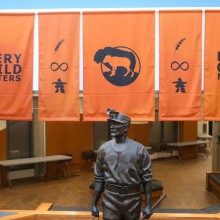Orange Every Child Matters banners hang in front of a statue