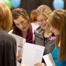 A group of people huddle around a table at a career fair.