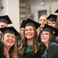A group of people in graduation caps and gowns gather for picture.