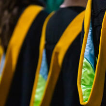 a row of students standing in graduation gowns.