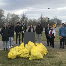 A group of people pose in front of several yellow garbage bags