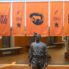 Orange Every Child Matters banners hang in front of a statue.