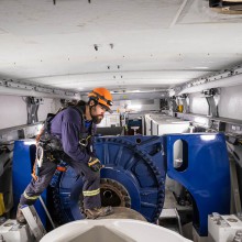 a man in blue coveralls works inside a wind turbine nacelle