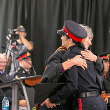 a woman in a police uniform hugs a college instructor at cadet graduation.