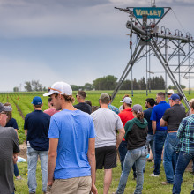 A group of people stand in a field near an irrigation pivot.