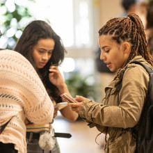 Two students look at their phones.