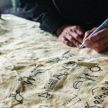 A close up of Indigenous symbols being painted on a buffalo robe.